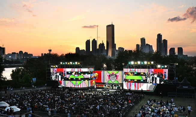 Grand concert de K-pop en plein air à Séoul, avec foule, scène géante et skyline au coucher du soleil