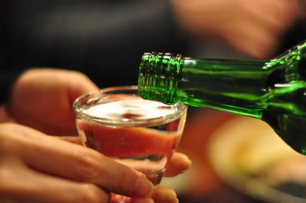 Gros plan sur un verre de soju que l’on remplit