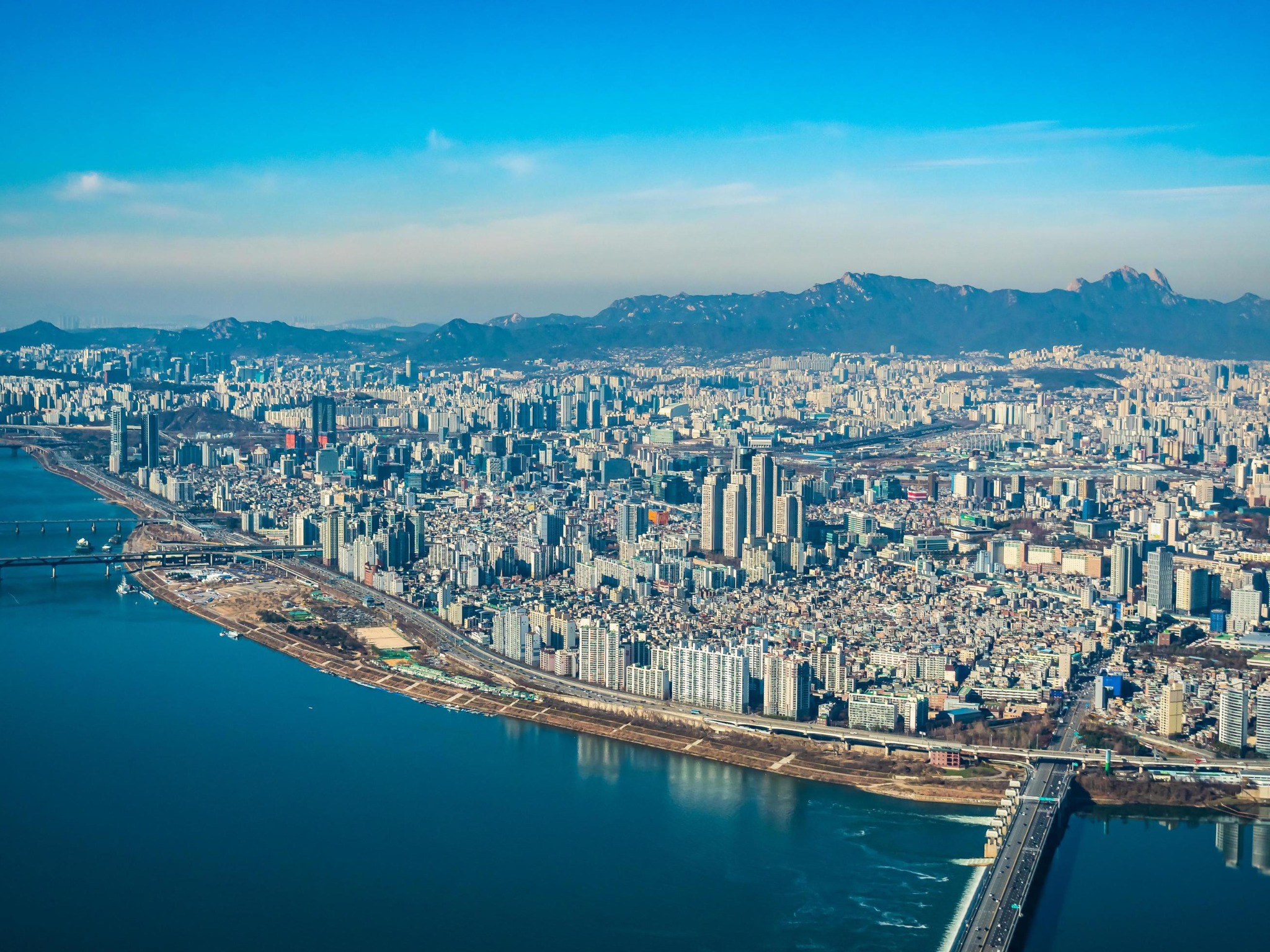 Vue aérienne de Séoul, du fleuve Han et de l’étendue urbaine jusqu’aux montagnes