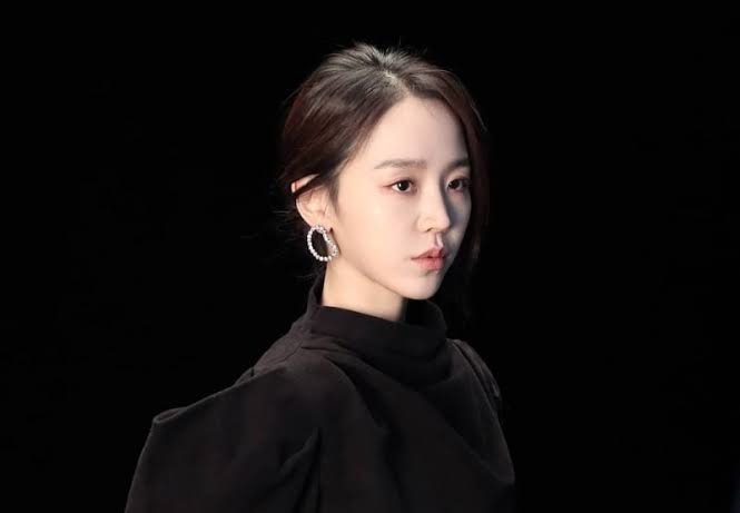 Portrait de Shin Hae-sun en tenue noire sur fond sombre